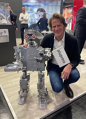 [Translate to English:] Harald Oberrauch mit Roboter am Stand von Alupress bei der Euroguss 2024